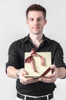 Hediye kutusu ışık gri arka plan üzerinde tutarak ve kameraya bakarak yakışıklı işadamı