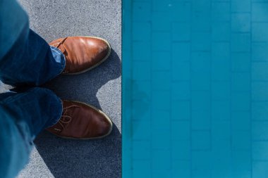 adam kahverengi deri ayakkabı terasında yüzme havuzu ve ücretsiz boşaltmak yakınındaki mavi jeans ile