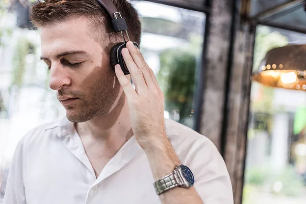 smart and handsome white man in white shirt listening music with happiness feeling with garden background