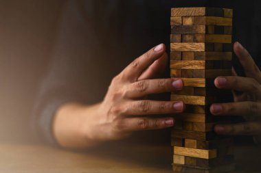 İşadamı ahşap masa üzerine ahşap blok inşa etmeye çalışıyor ve siyah arkaplan iş organizasyonu başlangıç konsepti