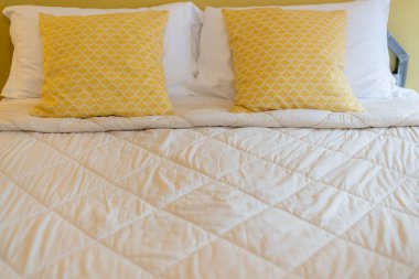 Yatak odasındaki yumuşak, sarı yastıklı güzel tasarım konsepti.