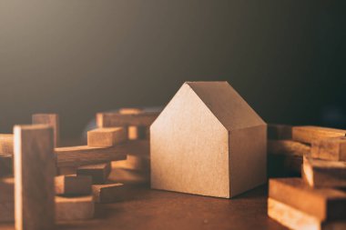 ev kağıdı modeli ve ahşap blok parçasıyla iş adamı düşüncesi ve endişesi ile varlık yatırımları kavramı