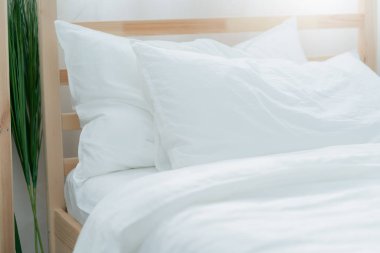 Yatak odasında temiz beyaz yastıkları ve çarşafları olan bir hizmetçi. Yakın plan. iç arkaplan