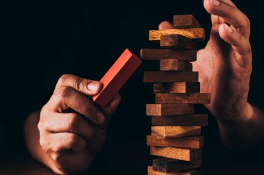 İşadamı ahşap masa üzerine ahşap blok inşa etmeye çalışıyor ve siyah arkaplan iş organizasyonu başlangıç konsepti