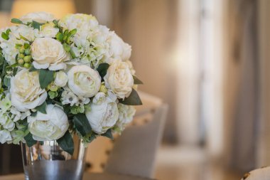 Beyaz buket çiçekli cam vazo. Oturma odasındaki iç mekan konseptine göre dekoratif eşyalar.