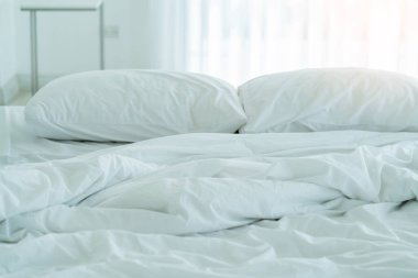 Yatak odasında temiz beyaz yastıkları ve çarşafları olan bir hizmetçi. Yakın plan. iç arkaplan