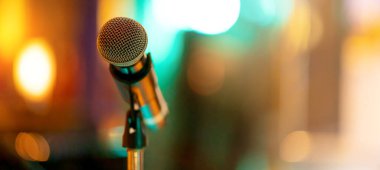 Konferans salonundaki renkli, soyut ışık saçan arka planlı yüksek kaliteli mikrofon ayarlarını kapat. Sahne pankartı boyutunda mikrofon.