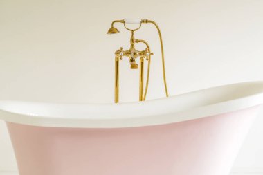 Eski tarz banyo küveti, beyaz arka planı olan altın rengi çelik musluk.