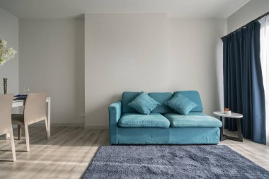 Mavi kanepe ve ahşap yemek masası iç dekorasyonlu minimal apartman tasarımı.
