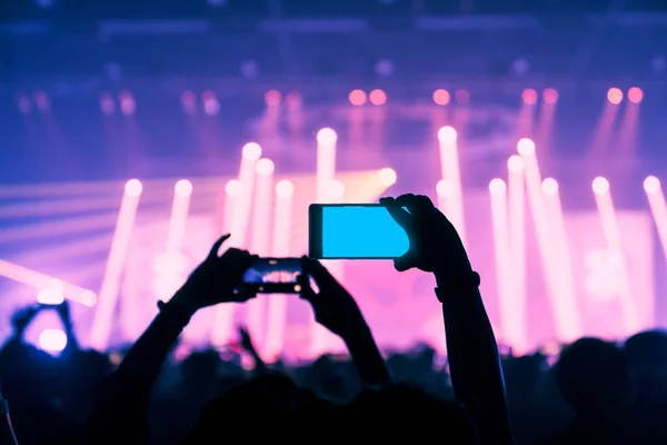ステージ上で光とレーザーの効果で素晴らしい瞬間を捉えるライブ音楽演奏会のハンドヘルドスマートフォンを楽しむ人たち — ストック写真