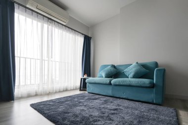 Beyaz oturma odasındaki mavi mercan kumaş renkli kanepe. İç dekorasyon konsepti.