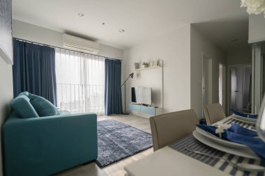 Mavi kanepe ve ahşap yemek masası iç dekorasyonlu minimal apartman tasarımı.