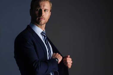 Zarif, beyaz, başarılı, sakallı bir iş adamı. Resmi takım elbise, gri arka plan.