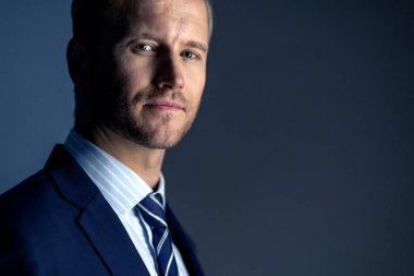 Zarif, beyaz, başarılı, sakallı bir iş adamı. Resmi takım elbise, gri arka plan.