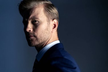 Zarif, beyaz, başarılı, sakallı bir iş adamı. Resmi takım elbise, gri arka plan.