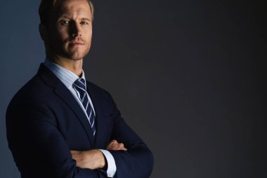 Zarif, beyaz, başarılı, sakallı bir iş adamı. Resmi takım elbise, gri arka plan.