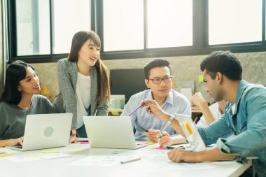 Bir grup iş arkadaşı gayri resmi bir toplantı yapıyor, iş adamları ofiste fikirleri tartışıyor.