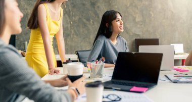 Bir grup iş arkadaşı Asyalı erkek ve kadın gayri resmi bir toplantı yapıyorlar. İş adamları ofiste fikirleri tartışıyor.