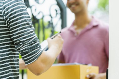 Teslimat fikirleri konsepti. Hindistan kurye paket ürününü müşteriye mutluluk ve neşe dolu ev kapısı girişi ile kapatın.