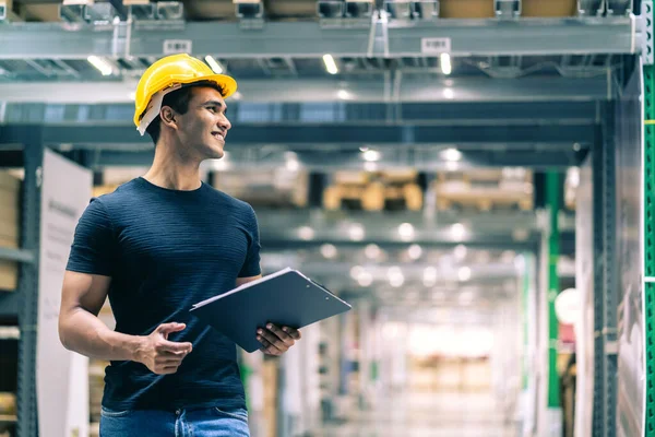 Güvenlik kaskı takan zeki Hintli mühendis fabrika deposunda hisse senedi kontrolü ve karton stok yönetimi yapıyor.