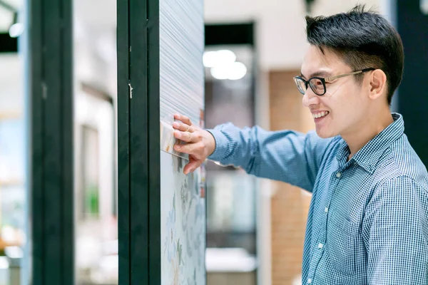 Asyalı akıllı erkek tasarımcı mutluluğu tasarım projesi için malzeme seçiyor
