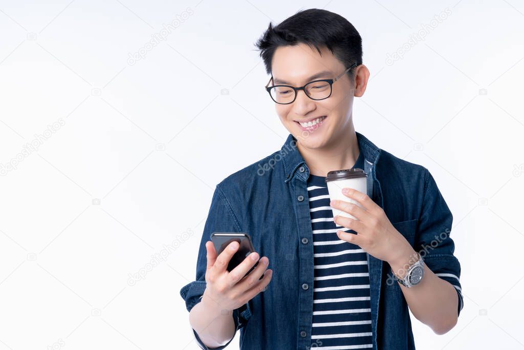smart attractive asian glasses male hand hold hot drink coffee hand search and look to smartphone screen with freshness and joyful casual dress white background