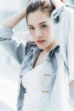 Kahverengi uzun saçlı, beyaz tişörtlü ve kot ceketli güzel bir kadın.