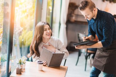 Çekici Asyalı kadın kafe restoranında garsonlu bir şeyler sipariş etti.