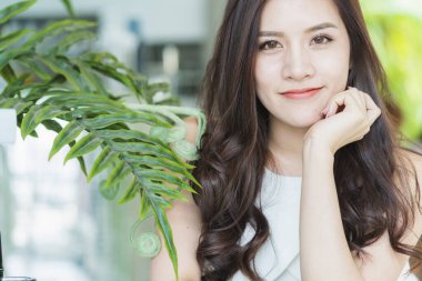 Güzel Asyalı kadın güzel gülümseme ve yeşil lealı sağlıklı cilt