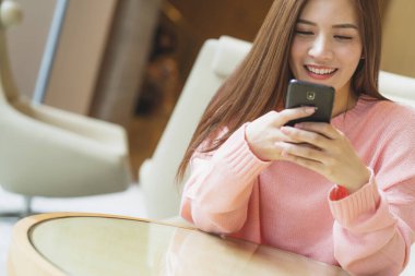 Güzel Asyalı kadın uzun kahverengi saçlı pembe kazaklı.