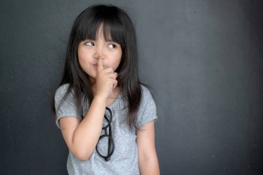 Mutluluk siyah saçlı Asyalı büyük gözlü kız portresi. Günlük elbise ve siyah perde arkasında eğlenceli bir fotoğraf çekimi.