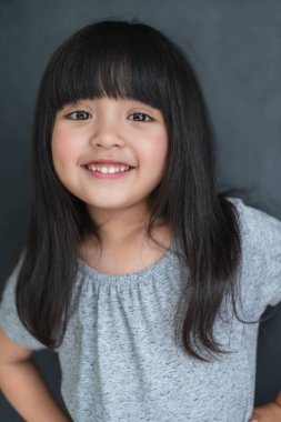 Mutluluk siyah saçlı Asyalı büyük gözlü kız portresi. Günlük elbise ve siyah perde arkasında eğlenceli bir fotoğraf çekimi.