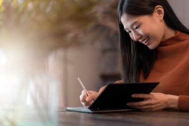 Güzel Asyalı Çinli kadın mutlu. Rahat ol. Günlük yaşam tarzını yazarken gülümse ve kafede neşelen.