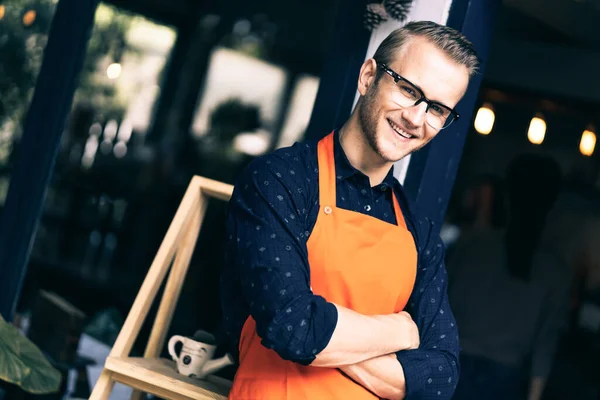 Portrait of happy young man wearing an apron attractive caucasian Male Barista cafe restaurant owner cross arms and smile with confident and warm welcome to his successful business place