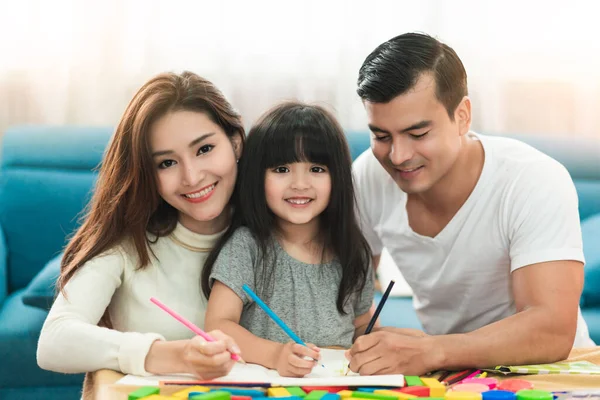 可愛い黒髪の子女の娘宿題とリビングの家のコンセプトで親と一緒に笑う — ストック写真