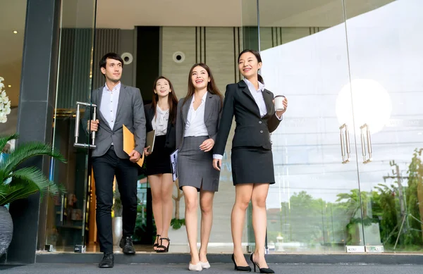 一群聪明的年轻亚洲商人男女正装走过现代写字楼入口 自信而快乐 — 图库照片