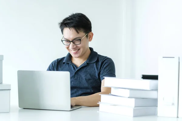 happiness glasses asian man work hand use laptop at home with smile and energy white room background