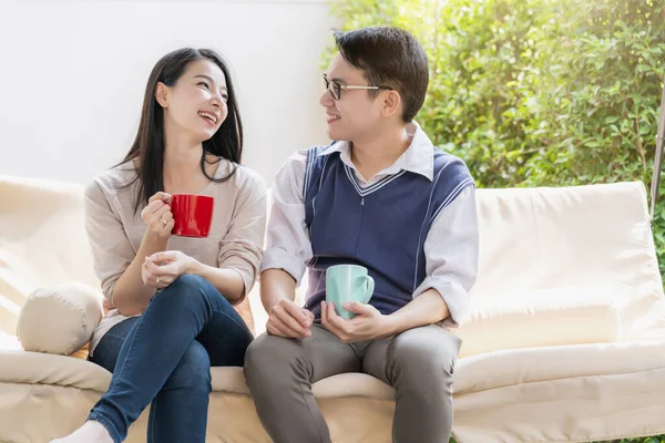 sweet and lovey asian couple husband and wife with hot drink talk together with happiness and peaceful home interior background