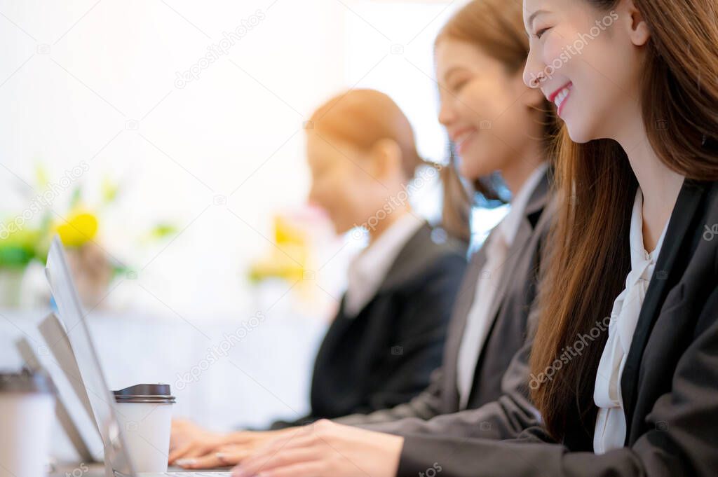 business asian female woman support service group working together with laptop with happiness and efficiency communication blur office background