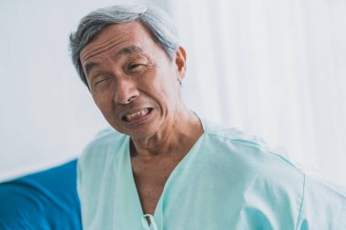 Ağrı ve sırt ağrısı. Hasta üniforması giyen yaşlı Asyalı büyükbaba vücut sorunları olan sağlık fikirleri kavramından muzdarip.