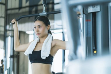 Güzel Asyalı spor kadını spor makinesiyle spor yaparken spor yaparken spor konsepti vücut geliştirici sağlıklı yaşam stili eğitimi alırken güzel kadın halterini kaldırıyor.