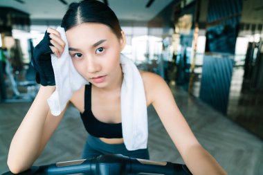güçlü ve sıkı Asyalı kadın spor giysileri bisiklet üzerinde rahat beyaz peçete fitness arka plan tutun