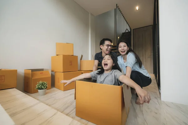 happiness asian family mom dad daughter moving in new house hand carry box of stuff with exited and fun cheerful expression