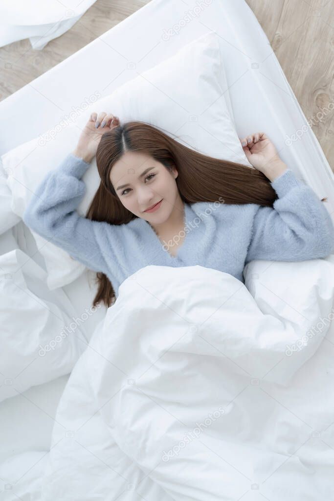 beautiful asian woman blue sweater lay done on white bed casual lifestyle morning time weekend concept top view