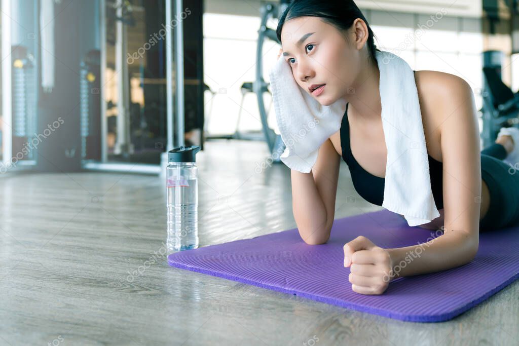 asian strong woman stretch and relax after workout gym fitness background on yoga mat
