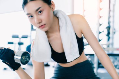 Güzel formda bir Asyalı kadın spor yaparken Dumbbell Bicep Bukleleriyle spor salonunda sağlıklı fikirler üretiyor.