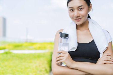 Güzel Asyalı kadın elinde su şişesi tutarak bahçe geçmişi olan sağlıklı fitness yoga egzersizi yapıyor.