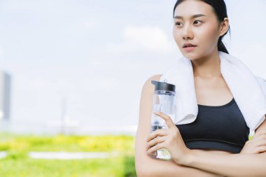 Güzel Asyalı kadın elinde su şişesi tutarak bahçe geçmişi olan sağlıklı fitness yoga egzersizi yapıyor.