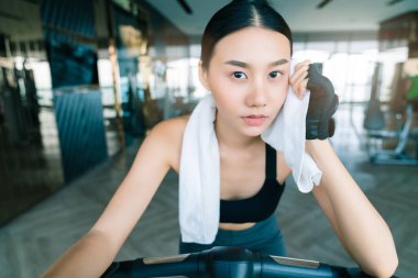 güçlü ve sıkı Asyalı kadın spor giysileri bisiklet üzerinde rahat beyaz peçete fitness arka plan tutun
