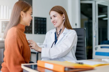 Asyalı kadın doktor göğüs kanseri semptomları, risk faktörleri ve klinikte hasta kontrolü.
